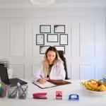a woman sitting at a desk in front of a laptop