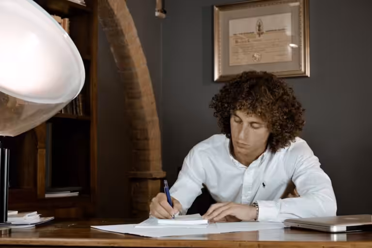 woman in white dress shirt holding pen writing on white paper