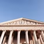 a tall building with columns and statues on top of it