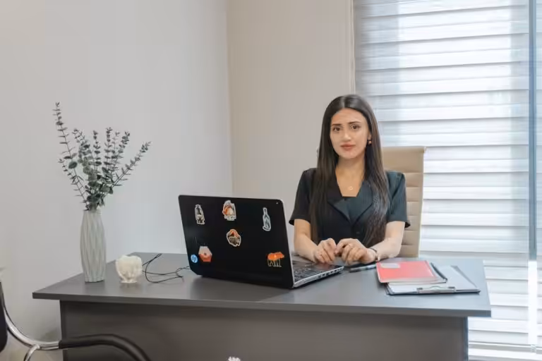 A woman sits at a desk with a laptop