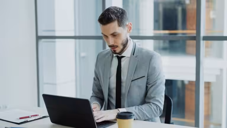 Man in suit working on a laptop at desk.