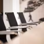 Black office chairs with chrome arms in a row at a conference table