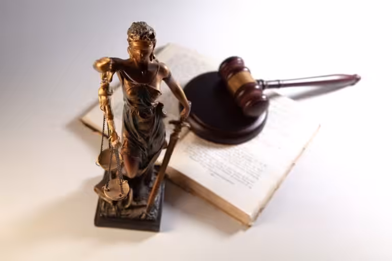 Statue of justice, gavel, and open book on table