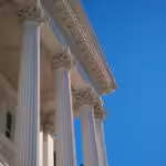 a tall white building with columns and a clock